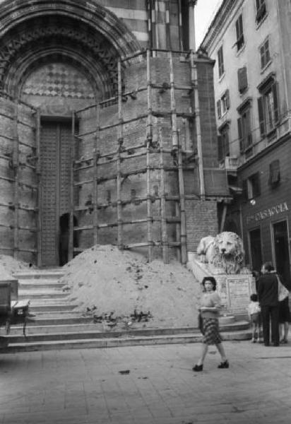 Italia Dopoguerra. Genova - Una donna attraversa la piazza davanti al portale della cattedrale di San Lorenzo in fase di ricostruzione