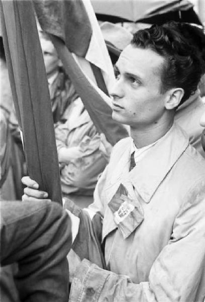 Referendum 1946 Repubblica o Monarchia. Milano - Piazza del Cannone - Manifestazione monarchica - Uomo con bandiera e adesivo del tricolore monarchico sull'impermeabile