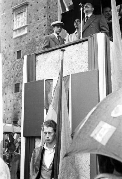 Referendum 1946 Repubblica o Monarchia. Milano - Piazza del Cannone - Manifestazione monarchica - Rappresentante politico al microfono dal palco - sotto un manifeastante fra le bandiere
