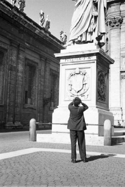 Roma. Piazza S. Pietro. Amico del gruppo di Patellani mentre scatta una fotografia accanto al basamento di una statua