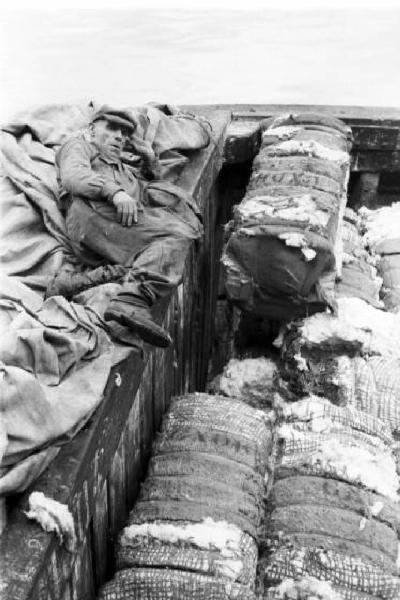 Italia Dopoguerra. Genova - Un uomo sdraiato sul molo si riposa accanto a un carico di cotone