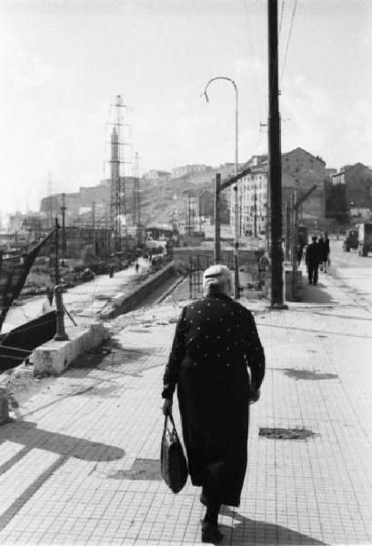 Italia Dopoguerra. Genova - Una donna cammina lungo la banchina del porto