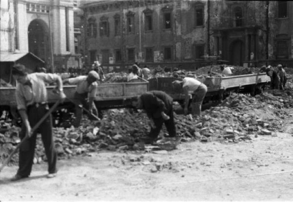 Italia Dopoguerra. Milano. Sgombero dalle macerie nel centro cittadino - spalatori caricano i materiali su appositi trenini