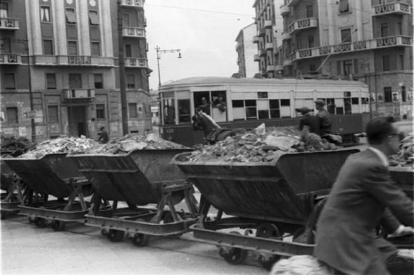 Italia Dopoguerra. Milano. Trenino speciale per la raccolta delle macerie - sullo sfondo un tram, un carro trainato da un cavallo e palazzi per abitazione