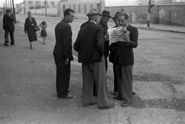 Italia Dopoguerra. Milano. Strada - Uomini discutono leggendo il giornale "L'Unità"