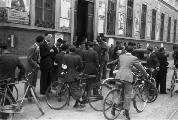 Referendum 1946 Repubblica o Monarchia. Milano - Ufficio elettorale - Cittadini a piedi e in bicicletta - Fascia con scudo crociato - Manifesti elettorali