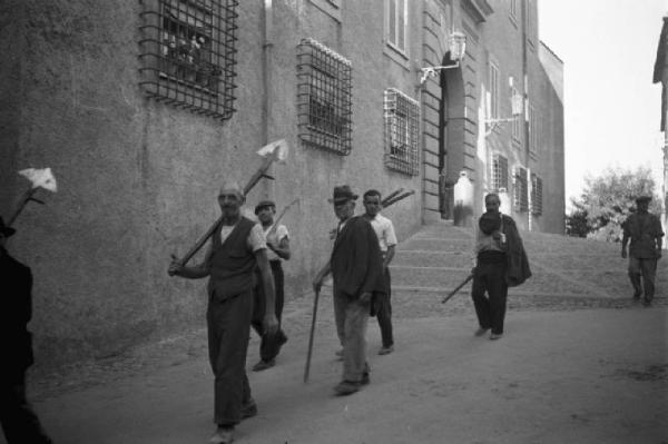 Invasione delle terre. Contadini con attrezzi agricoli in cammino accanto al Palazzo Pontificio