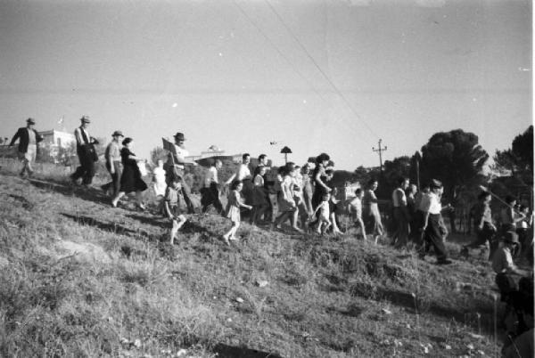 Invasione delle terre. Contadini che manifestano, camminando in discesa per un prato