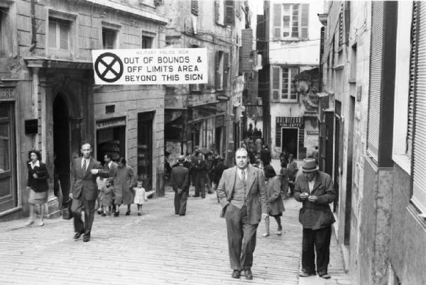 Italia Dopoguerra. Genova - Scorcio di una strada affollata della città con un cartello in lingua inglese che definisce l'area "off limits" durante il periodo di guerra