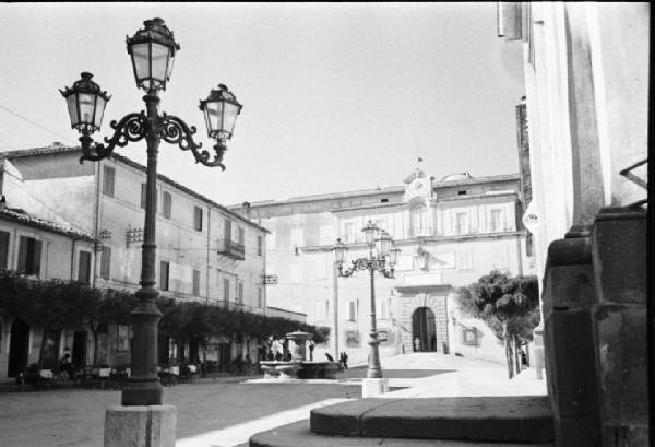 Invasione delle terre. Veduta della piazza di Castelgandolfo con l'ingresso al Palazzo Pontificio. Lampione in primo piano