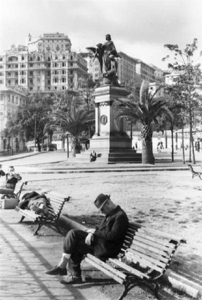 Italia Dopoguerra. Genova - Scorcio di una piazza della città - alcuni uomini si riposano dormendo sulle panchine dei giardini pubblici