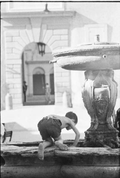 Invasione delle terre. Un bambino gioca sulla fontana della piazza di Castelgandolfo