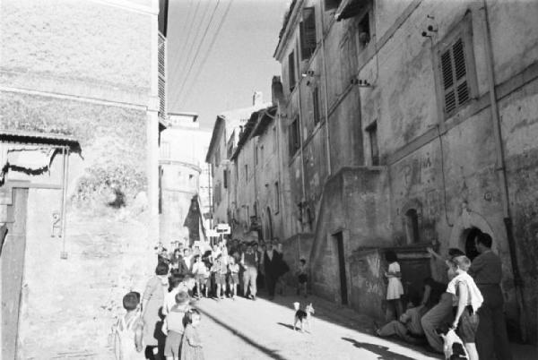 Invasione delle terre. Gruppo di contadini manifesta sfilando nei vicoli di Castelgandolfo. Bambini osservano la scena