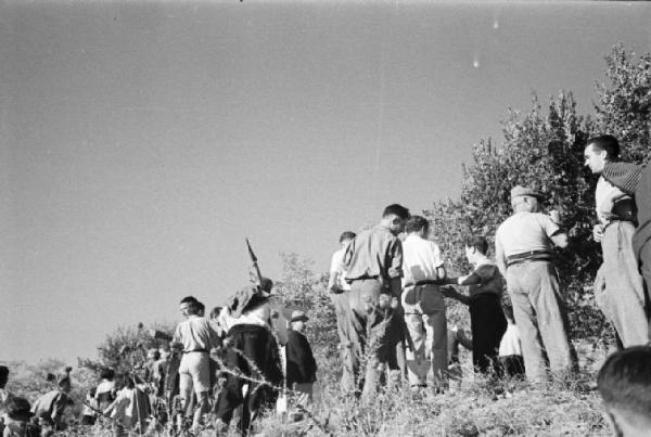 Invasione delle terre. Gruppo di contadini che manifestano in un prato con cartelli e bandiere