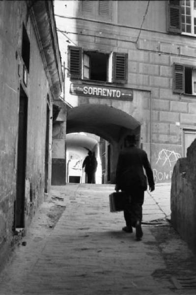 Italia Dopoguerra. Genova - Passaggio porticato - uomo - insegna di trattoria