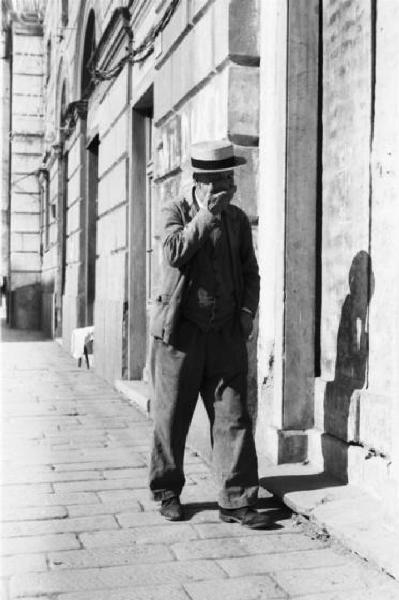 Italia Dopoguerra. Genova - Un uomo anziano sbadiglia mentre cammina per strada