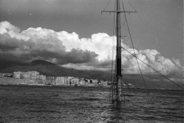 Italia Dopoguerra. Genova - Porto - veduta del mare con relitto di una nave di cui affiora soltanto l'albero maestro