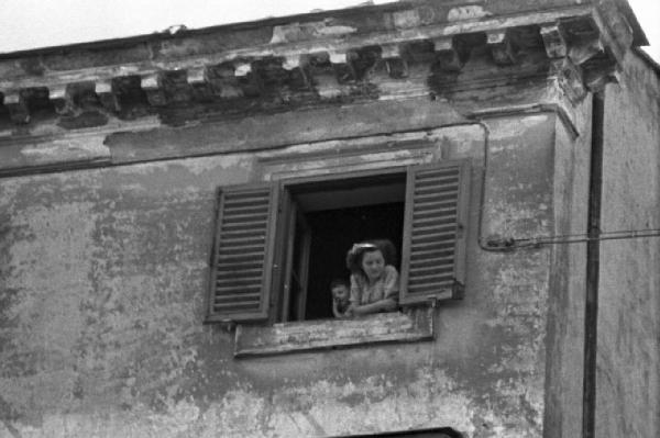 Ike a Castel Gandolfo. Donna e bambino affacciati alla finestra di un palazzo guardano verso il basso