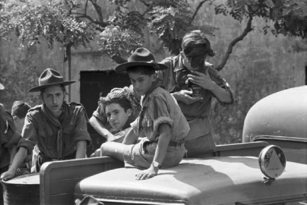 Ike a Castel Gandolfo. Gruppo di giovani scout sulla carrozzeria di un automezzo. Uno di essi osserva attraverso una macchina fotografica