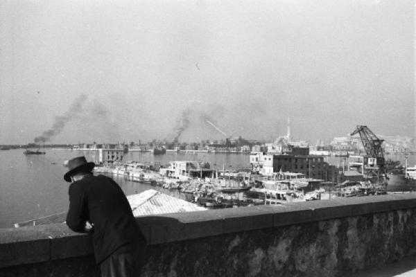 Italia Dopoguerra. Genova - Uomo affacciato a un parapetto nei pressi del porto