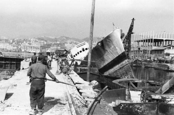 Italia Dopoguerra. Genova - La ricostruzione del porto - operai al lavoro sul molo dove si trova il relitto di una nave