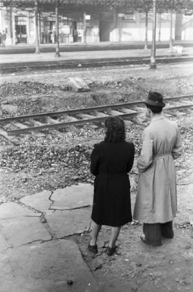 Stazione ferroviaria di Piacenza - due viaggiatori sorpresi di spalle durante l'attesa del treno
