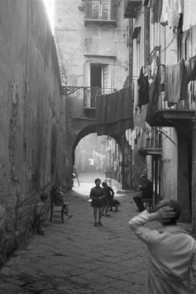 Italia Dopoguerra. Napoli. Scene di vita quotidiana lungo un vicolo, bambini e persone. Panni stesi all'esterno delle abitazioni