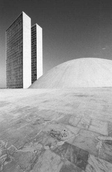 Brasilia. Bicicletta da corsa davanti a una delle due cupole del Congresso Nazionale, con i due grattacieli sullo sfondo