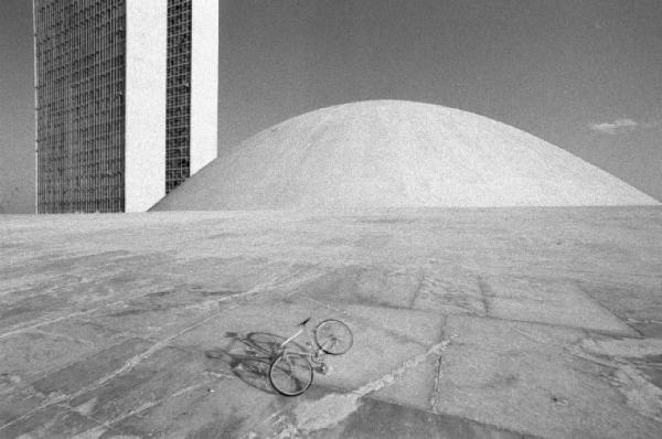 Brasilia. Bicicletta da corsa davanti a una delle due cupole del Congresso Nazionale, con i due grattacieli sullo sfondo