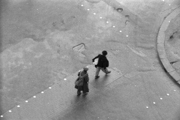 Italia Dopoguerra. Napoli. Due uomini ripresi dall'alto attraversano una strada