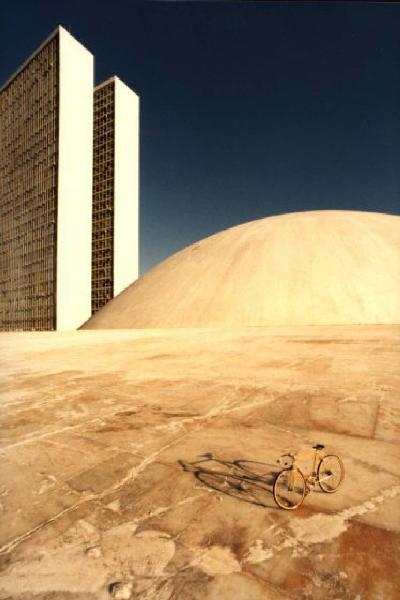 Brasilia. Bicicletta da corsa davanti a una delle due cupole del Congresso Nazionale, con la base del doppio grattacielo sullo sfondo