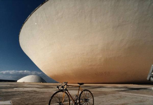 Brasilia. Bicicletta da corsa davanti a una delle due cupole del Congresso Nazionale, con l'altra sullo sfondo