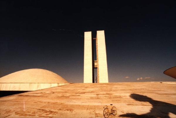 Brasilia. Bicicletta da corsa davanti al doppio grattacielo del Congresso Nazionale. Si nota un'ombra di persona sulla spianata lastricata