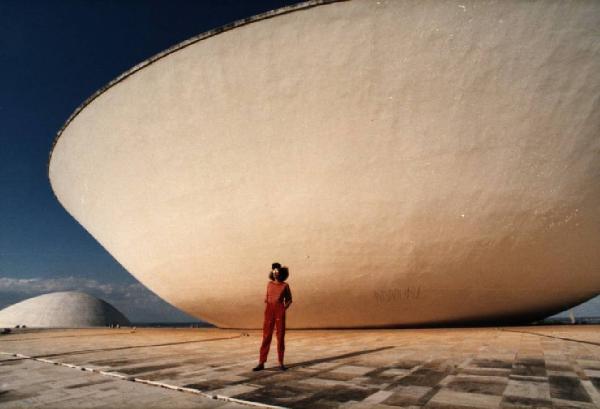 Brasilia. Figura femminile (Cyssa) davanti a una cupola del Congresso Nazionale, con l'altra sullo sfondo