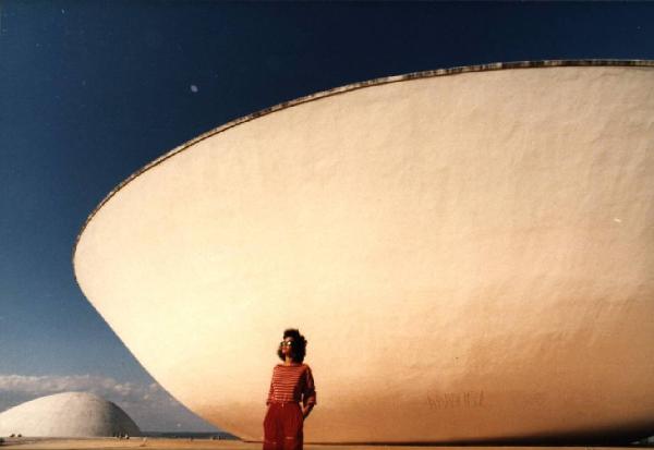 Brasilia. Figura femminile (Cyssa) davanti a una cupola del Congresso Nazionale, con l'altra sullo sfondo