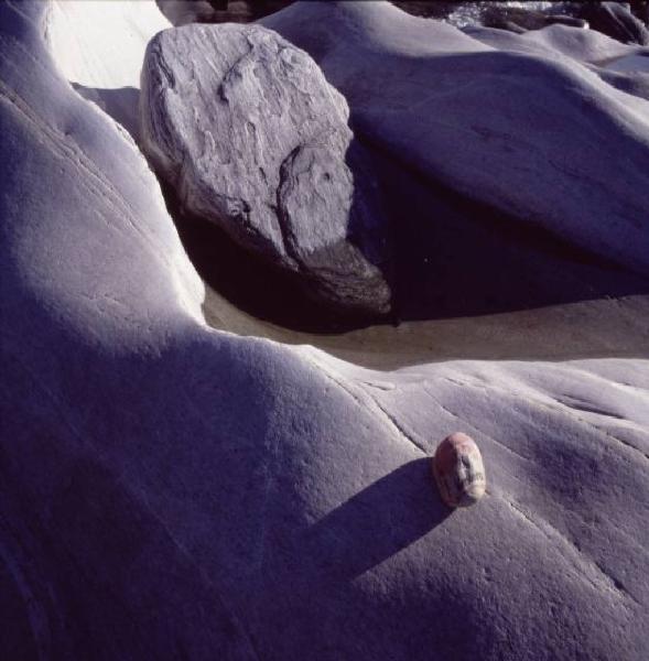 Marlboro. Sasso dipinto come il pacchetto di sigarette appoggiato sulle rocce accanto a un corso d'acqua