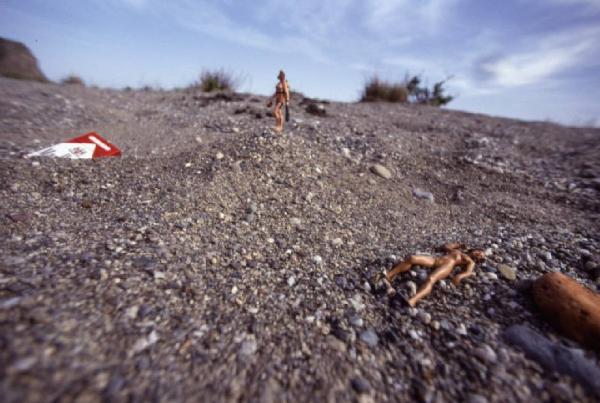 Marlboro. Pacchetto di sigarette con piccola bambole nude in pose da modelle, su cumulo di ghiaia