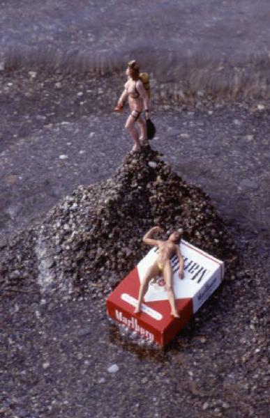 Marlboro. Pacchetto di sigarette sulla spiaggia, con piccole bambole nude intorno