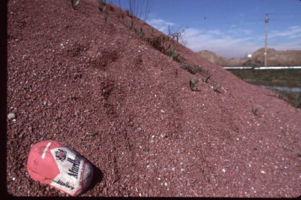 Marlboro. Sasso dipinto come il pacchetto di sigarette, appoggiato su un cumulo di ghiaia rossa