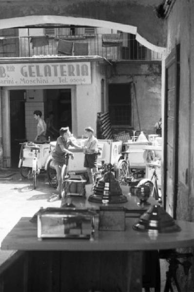 Milano. Carretti del gelato parcheggiati in un cortile - due ragazzini chiacchierano tra loro