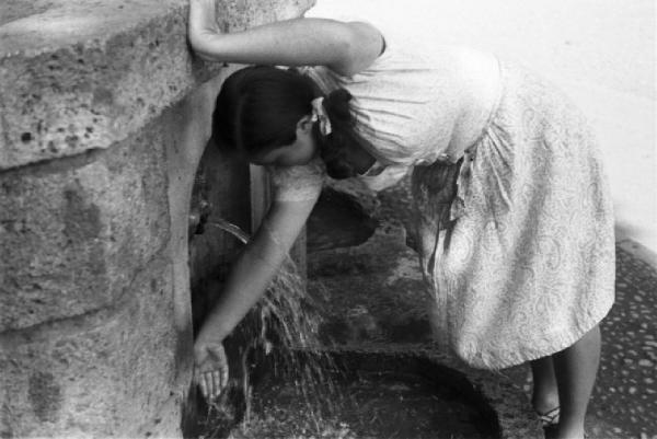 Milano. Parco Sempione. Una ragazza si rinfresca bagnandosi le braccia alla "Fontana dell'acqua marcia"