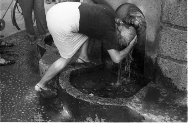 Milano. Parco Sempione. Una donna si rinfresca bagnandosi il capo alla "Fontana dell'acqua marcia"