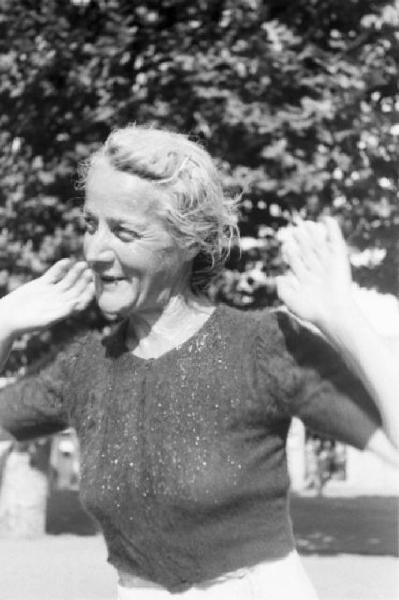 Milano. Parco Sempione. Donna anziana gesticola sorridente mentre chiacchiera nei pressi della "Fontana dell'acqua marcia"