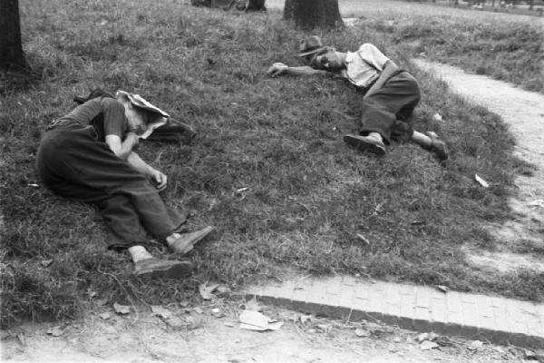 Milano. Parco Sempione. Alcune persone sdraiate a riposare sull'erba - coppia seduta sul prato a chiacchierare