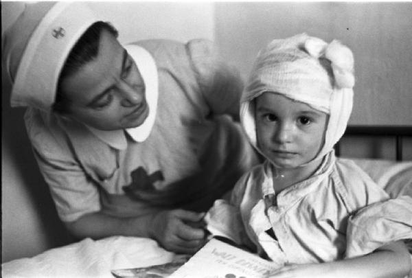 Diano Marina. Ospedale. Malati di tifo. Reparto bambini - un paziente con il capo fasciato assistito da una crocerossina