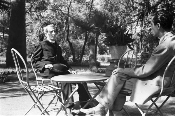 Roma. Don Luigi Sturzo seduto al tavolino di un parco con un fotografo