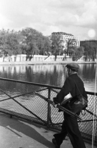 Parigi. Artista di strada, con i propri strumenti di lavoro sottobraccio, che cammina lungo la Senna