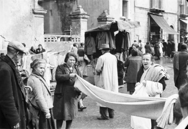 Italia Dopoguerra. Napoli. Venditrici lungo le vie della città piegano delle coperte