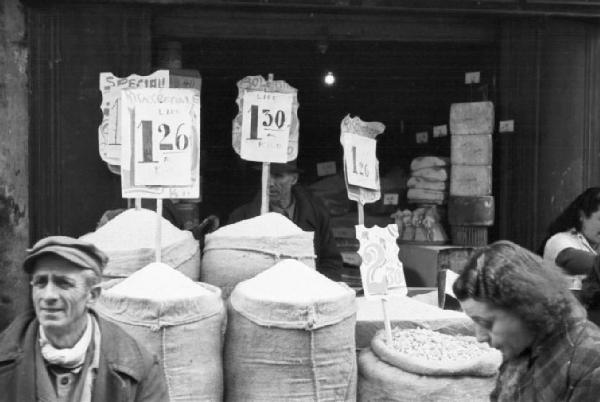 Italia Dopoguerra. Napoli. Sacchi di cereali in esposizione di fronte ad un negozio