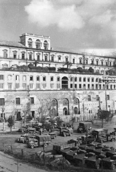 Italia Dopoguerra. Napoli. Automezzi militari parcheggiati di fronte a un edificio storico